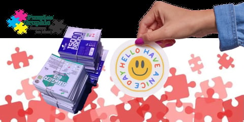 Hand holding puzzle piece over stack of purple QR code cards with smile logo and scattered pink puzzle pieces on white background